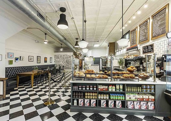 3 - Interior of coffee shop and bakery showing baked goods on display and long banquette with tables 3 - Interior of coffee shop and bakery showing baked goods on display and long banquette with tables